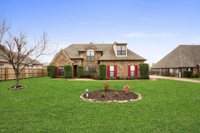 french country inspired facade with a shingled roof, brick siding, fence, and a front lawn