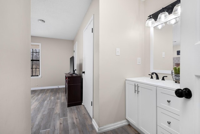 bathroom featuring a textured ceiling, vanity, baseboards, and wood finished floors