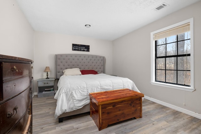 bedroom with baseboards, visible vents, and light wood-style floors