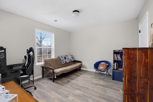 office space with a textured ceiling, light wood finished floors, and baseboards