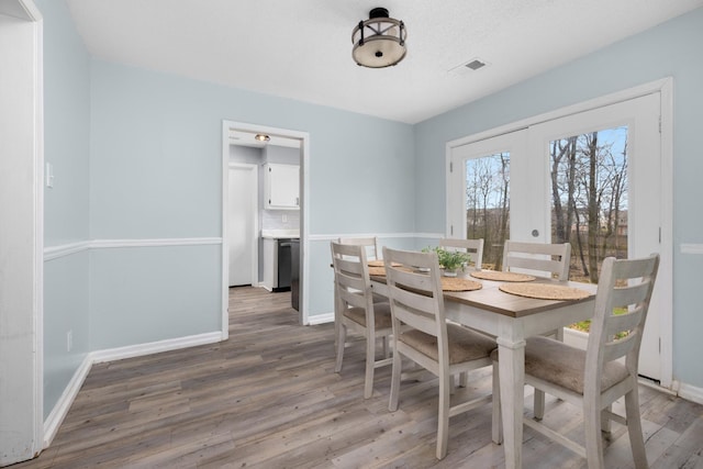 dining space featuring french doors, wood finished floors, visible vents, and baseboards