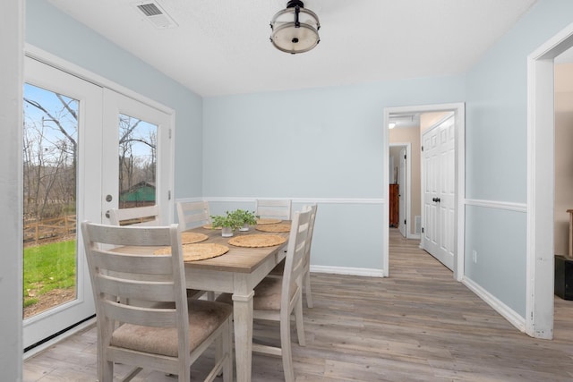 dining area with a healthy amount of sunlight, light wood-style floors, baseboards, and visible vents