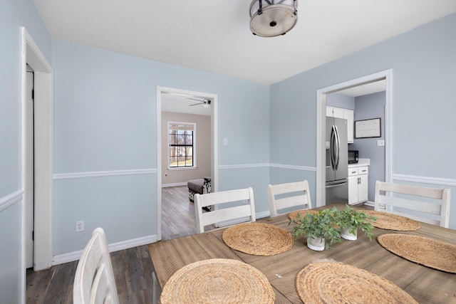 dining space featuring dark wood-type flooring and baseboards