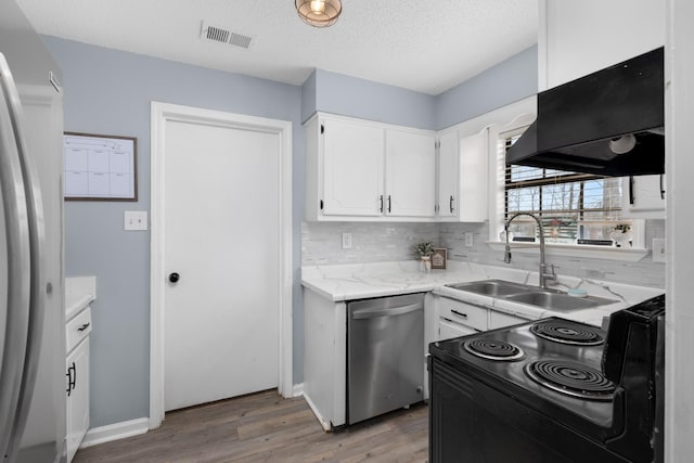 kitchen featuring premium range hood, a sink, visible vents, white cabinets, and appliances with stainless steel finishes