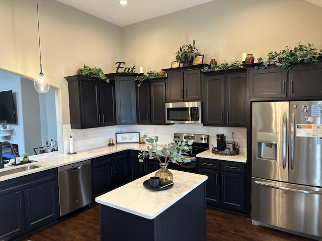 kitchen with dark wood-type flooring, pendant lighting, stainless steel appliances, and a sink