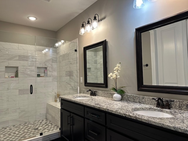 full bathroom featuring double vanity, a sink, and a shower stall