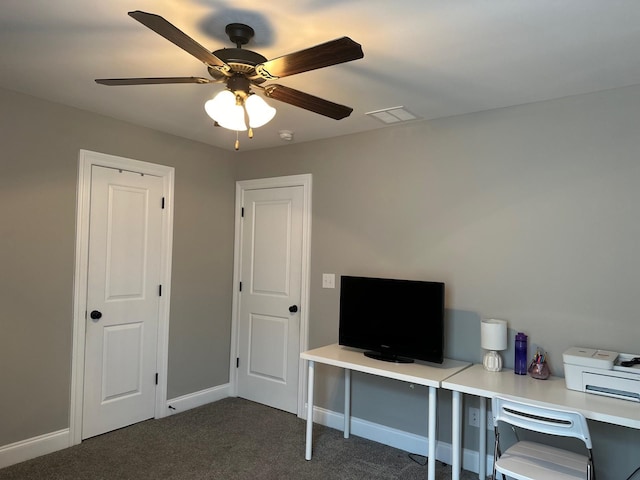 unfurnished office featuring a ceiling fan, visible vents, dark carpet, and baseboards