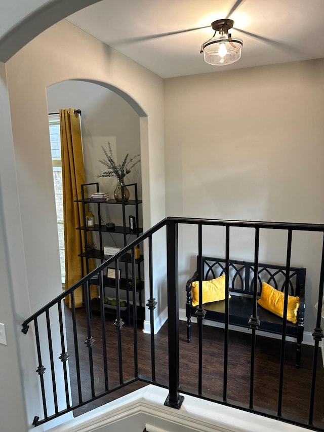 stairway with arched walkways and wood finished floors