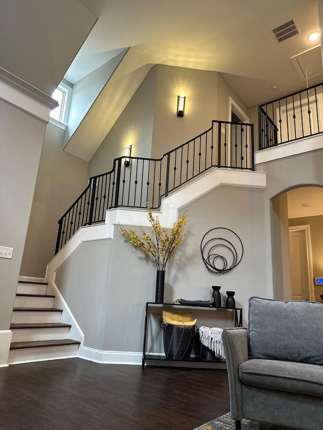 staircase featuring a towering ceiling, attic access, visible vents, and wood finished floors