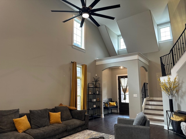 living area with arched walkways, dark wood-type flooring, stairway, and a ceiling fan