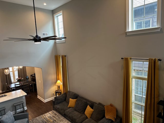 living room featuring baseboards, visible vents, arched walkways, a ceiling fan, and dark wood-style floors