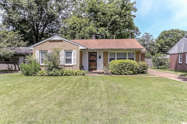 ranch-style house with brick siding, a chimney, and a front lawn