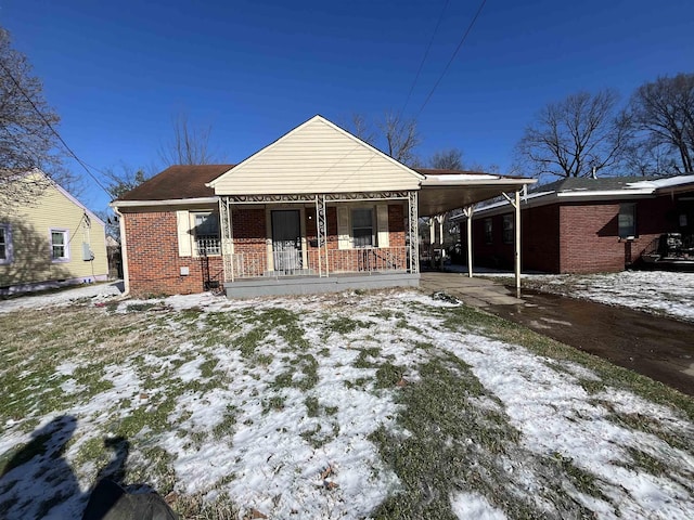 view of front of home with a porch, an attached carport, and brick siding