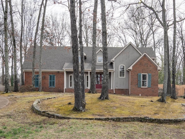 view of front of property featuring a shingled roof, brick siding, and a front lawn