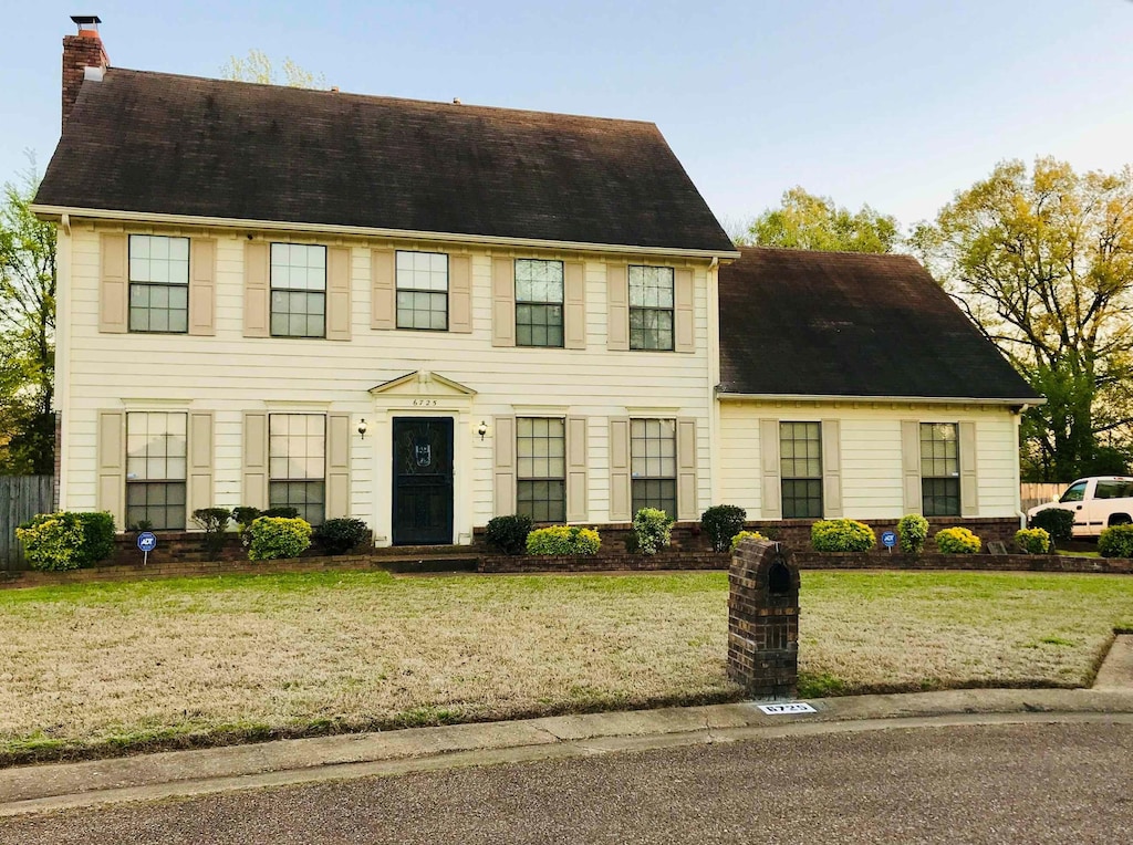 view of front facade with a chimney and a front lawn