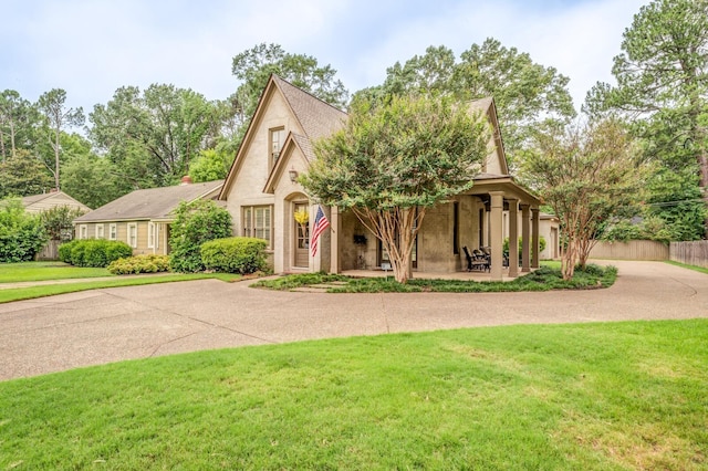 tudor home featuring a patio area, fence, and a front lawn