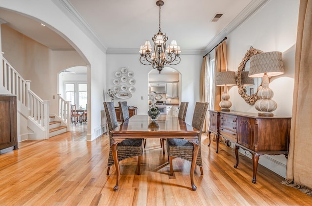 dining room featuring visible vents, arched walkways, light wood-style flooring, stairs, and a chandelier