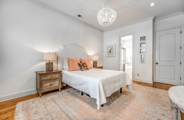 bedroom featuring baseboards, visible vents, crown molding, and wood finished floors