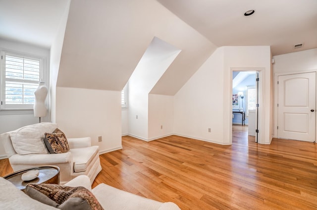 sitting room with light wood-style floors, visible vents, vaulted ceiling, and baseboards