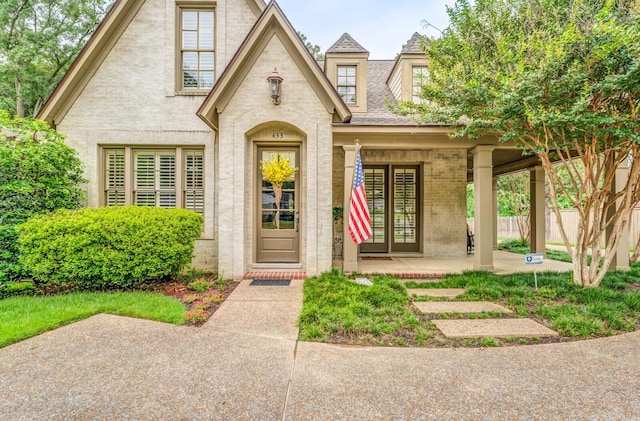 view of front of property with roof with shingles, fence, a porch, and brick siding