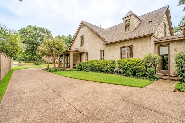 view of property exterior with a shingled roof, fence, a patio, and a yard