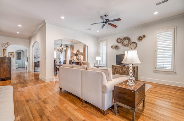 living area with arched walkways, baseboards, visible vents, and light wood finished floors