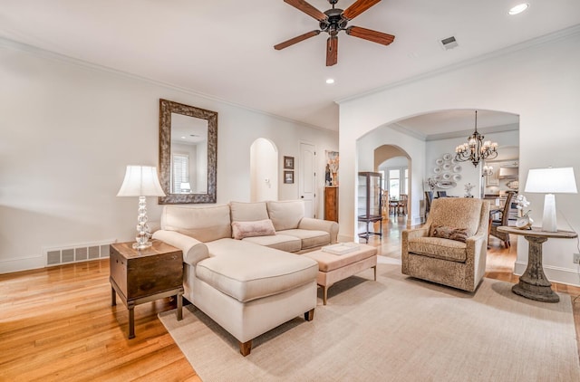 living area with arched walkways, light wood-style flooring, visible vents, and baseboards