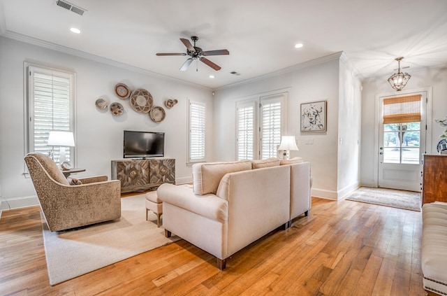 living area with ornamental molding, baseboards, visible vents, and light wood finished floors