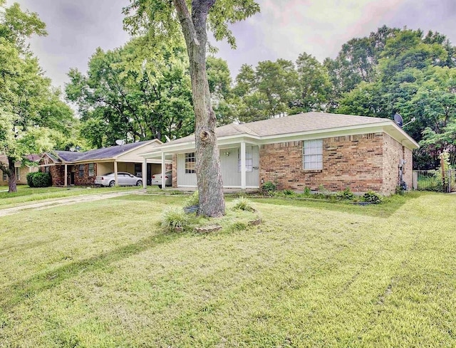 single story home featuring an attached carport, a front yard, and brick siding