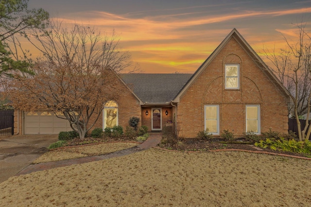 view of front of home with concrete driveway, brick siding, roof with shingles, and an attached garage