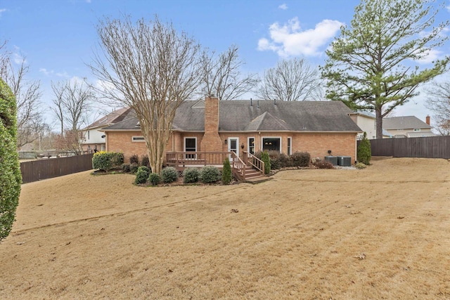 back of property featuring a fenced backyard, a chimney, a wooden deck, central AC, and brick siding