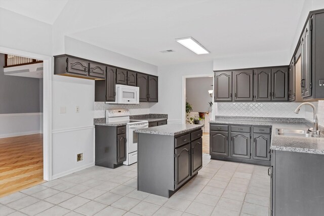 kitchen featuring white appliances, a kitchen island, a sink, and light tile patterned flooring