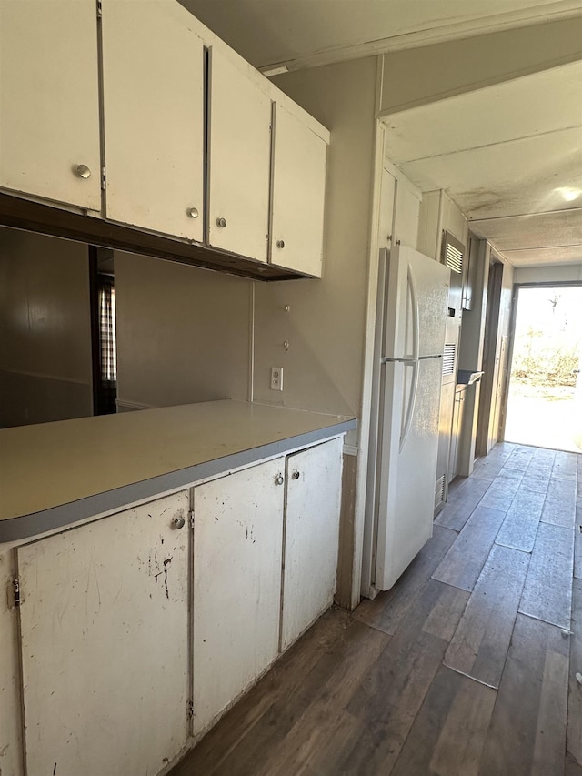 kitchen with freestanding refrigerator, white cabinets, light countertops, and dark wood-style flooring