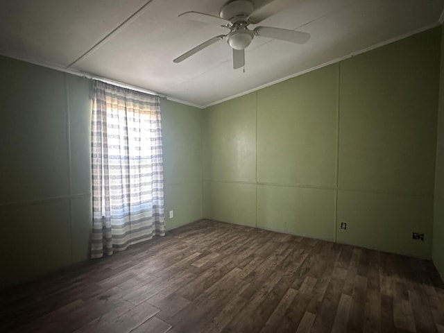 spare room with dark wood-style floors, ornamental molding, and a ceiling fan