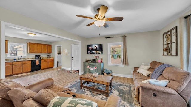 living area with light wood finished floors, a ceiling fan, and baseboards