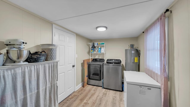 washroom with water heater, laundry area, washer and clothes dryer, and light wood-type flooring