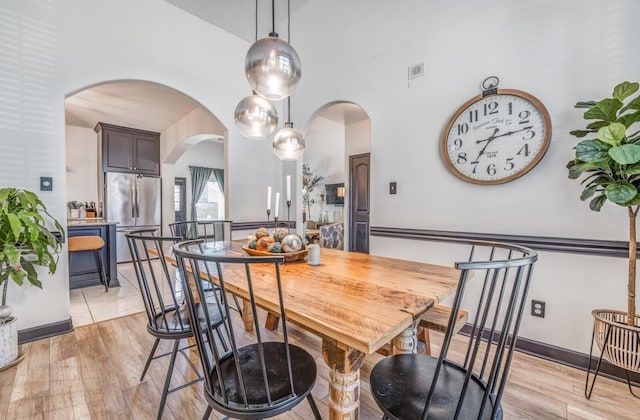 dining room featuring light wood-style floors and arched walkways