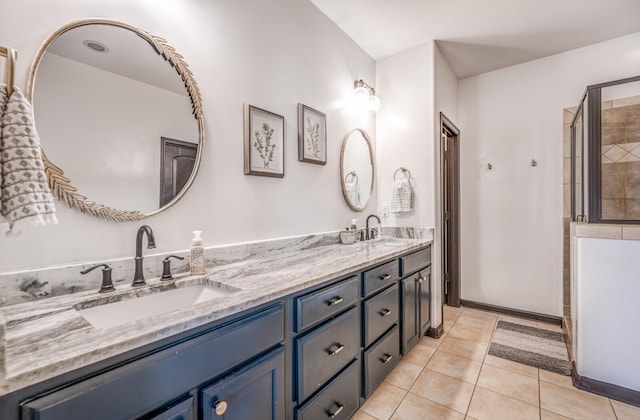 bathroom with double vanity, tiled shower, a sink, and tile patterned floors