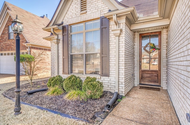 doorway to property with brick siding and an attached garage