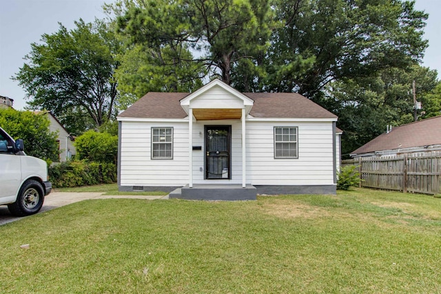 bungalow-style home featuring a shingled roof, crawl space, a front yard, and fence