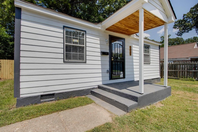 entrance to property with a yard, crawl space, and fence