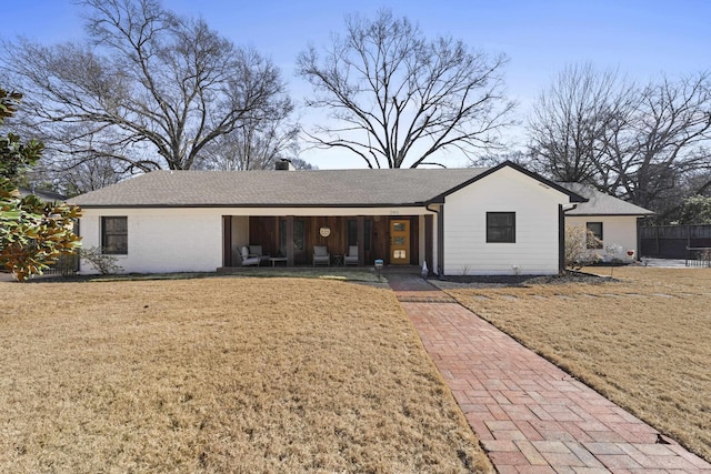 ranch-style home featuring covered porch and a front lawn