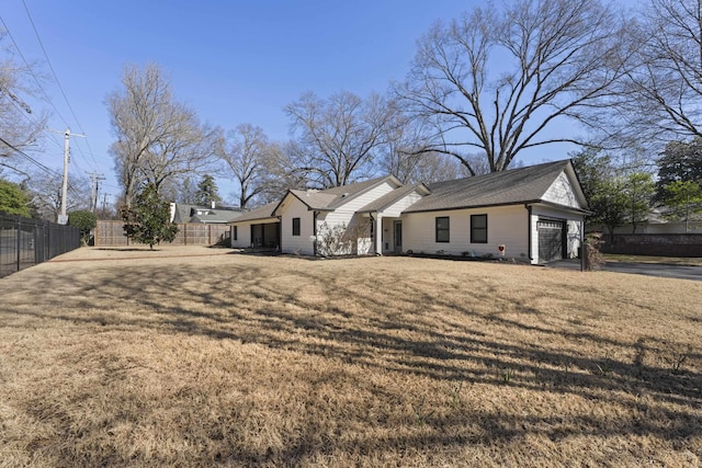 view of front of house with an attached garage, fence, and a front yard