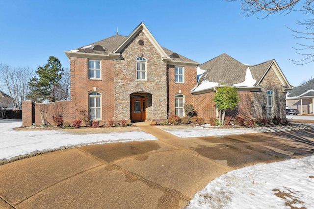 view of front of property with stone siding, brick siding, and a shingled roof