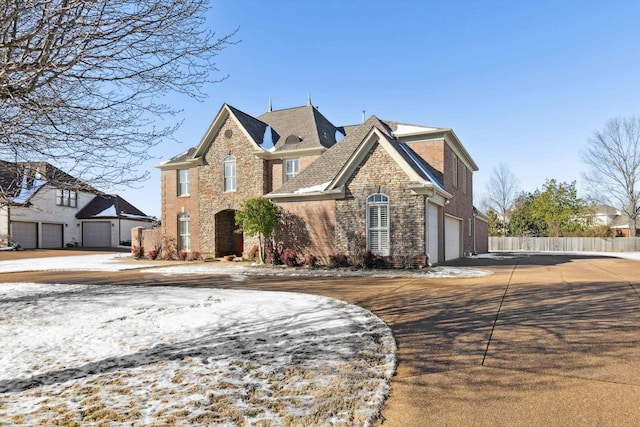 traditional-style home with stone siding, concrete driveway, fence, and an attached garage