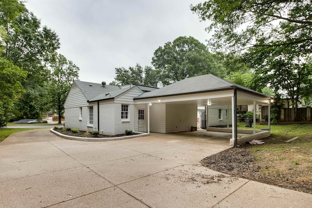 view of front of house featuring driveway, fence, a carport, and brick siding