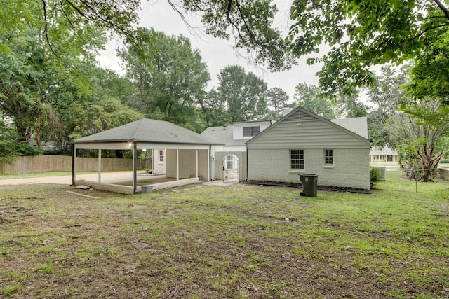 rear view of house with a fenced backyard, a patio, brick siding, and a lawn