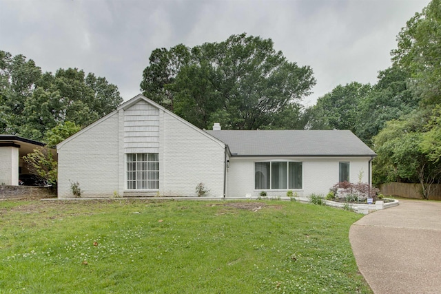 rear view of property featuring brick siding and a lawn