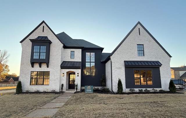 view of front of house featuring a standing seam roof, a front yard, metal roof, and brick siding