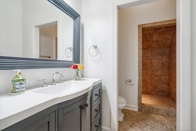 bathroom with tiled shower, vanity, toilet, and tile patterned floors